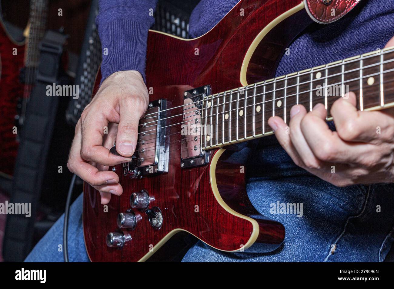 Si tratta di un'immagine ravvicinata di una persona che suona abilmente una chitarra elettrica, mostrando le mani e i dettagli dello strumento che sta usando Foto Stock