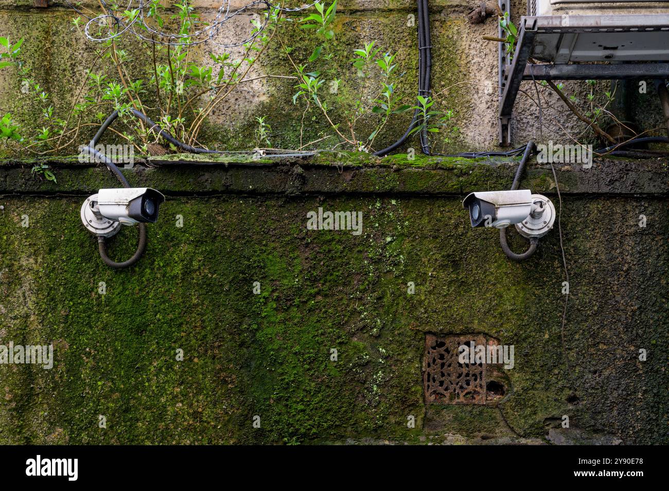 Due telecamere di sicurezza a circuito chiuso che si guardano e si guardano su un muro esterno Foto Stock