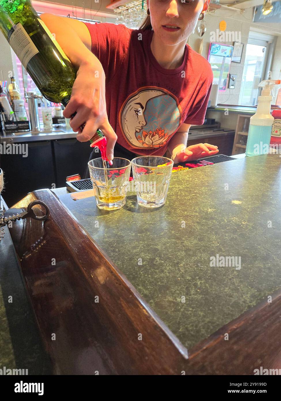 Una barista donna versa due shot di Jameson Whisky al bancone Foto Stock