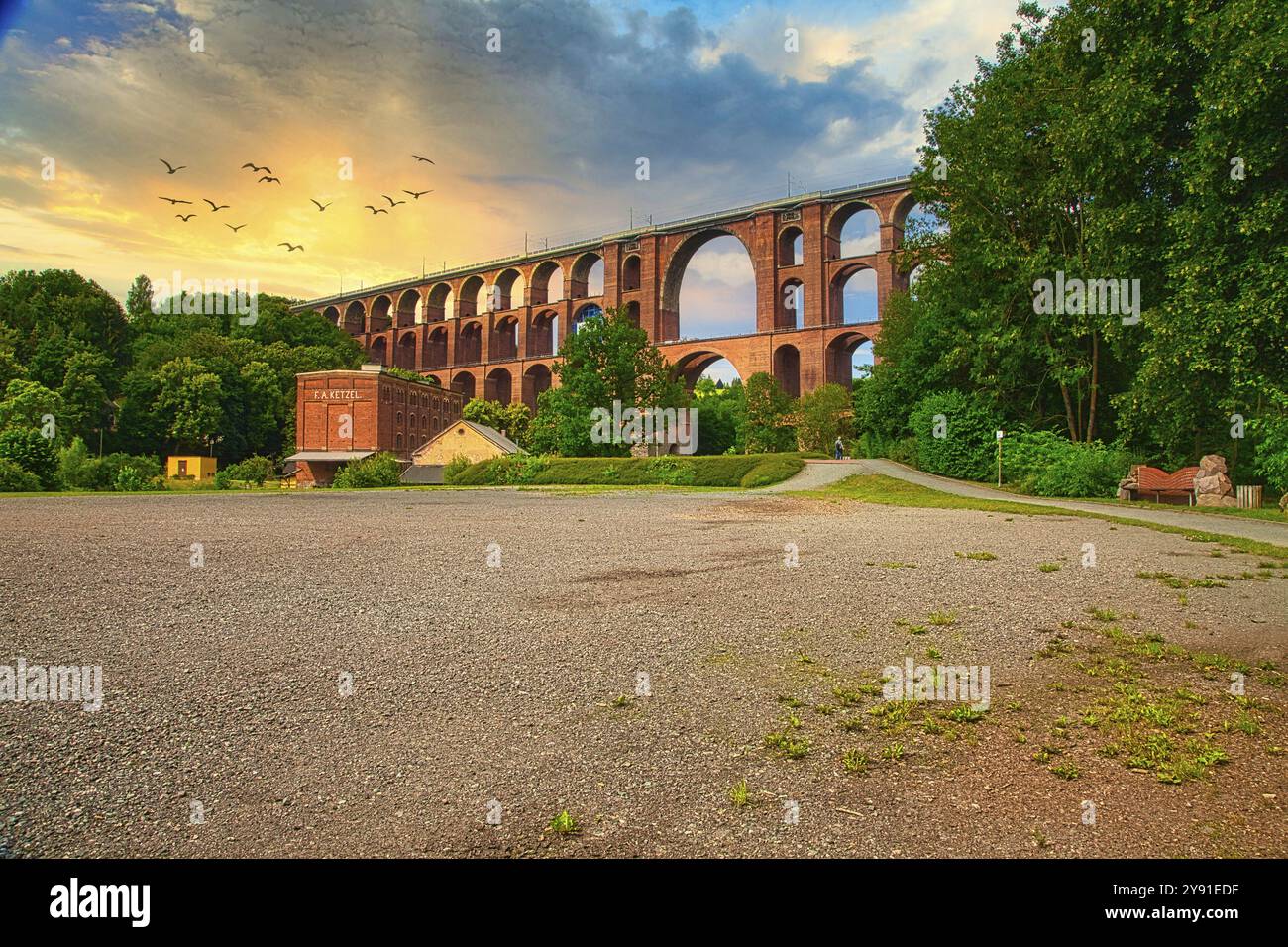 Lo storico ponte Goeltzschtal si estende su un paesaggio verde al tramonto con nuvole e uccelli volanti, Vogtland, Sassonia, Germania, Europa Foto Stock