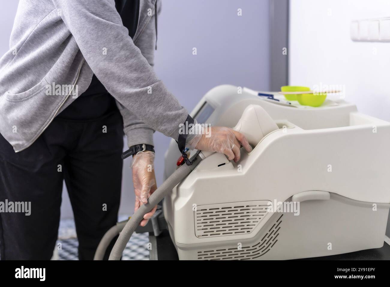 Estetista che tiene in mano una moderna macchina laser in una clinica pronta per il trattamento di epilazione Foto Stock