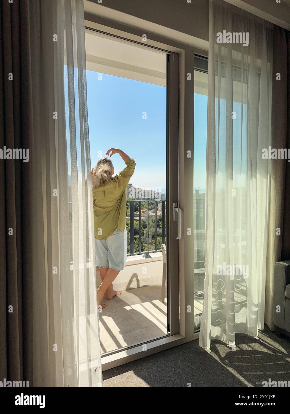 Una donna in piedi sul balcone durante il giorno di sole estivo in Montenegro Foto Stock