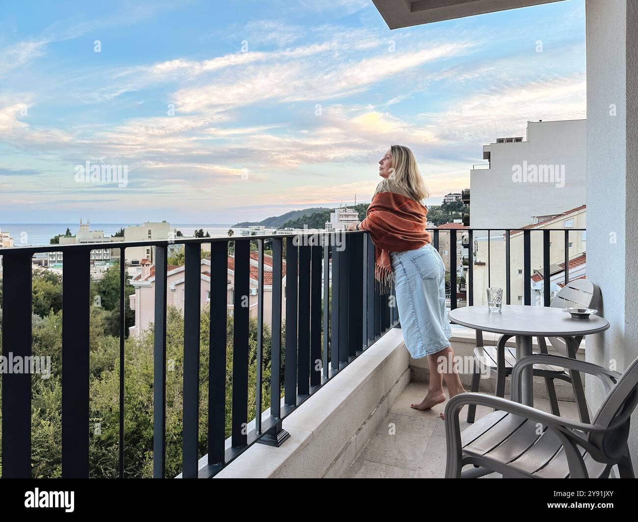 Una donna in piedi sul balcone al tramonto estivo in Montenegro Foto Stock