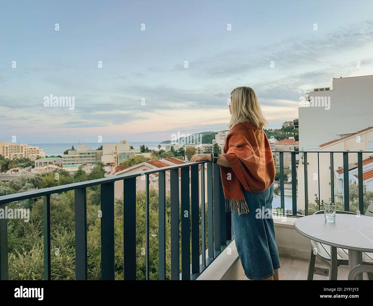 Una donna in piedi sul balcone al tramonto estivo in Montenegro Foto Stock