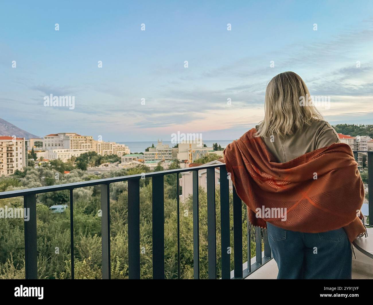 Una donna in piedi sul balcone al tramonto estivo in Montenegro Foto Stock