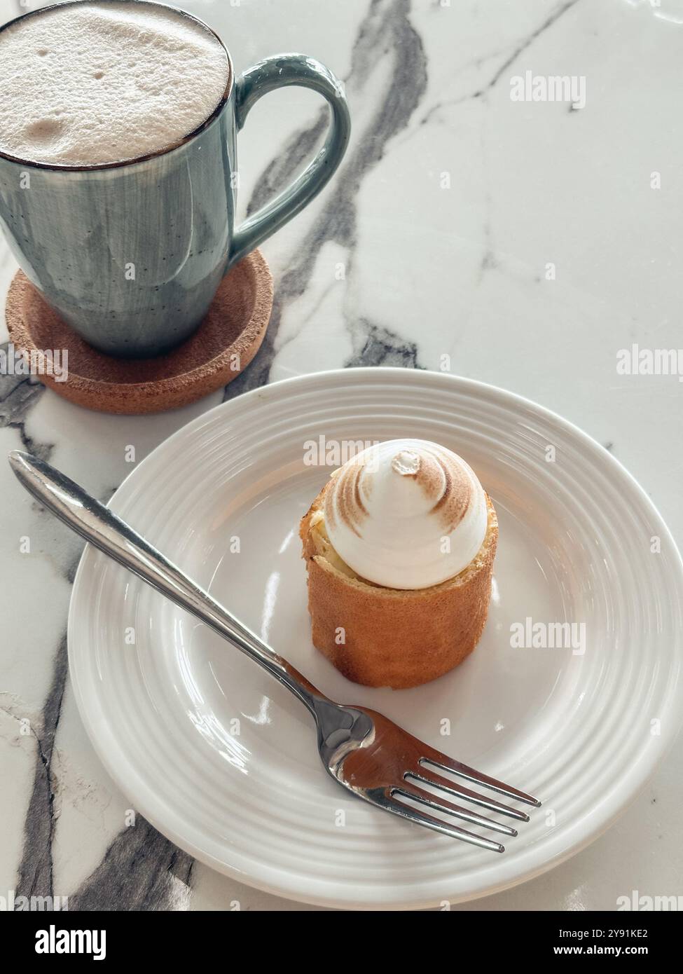 Caffè in tazza blu e torta al limone con meringa sul tavolo di marmo Foto Stock