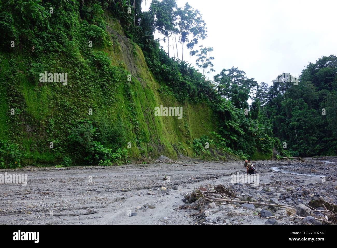 Guida che guida il turista in moto fino al canyon di cenere formato dal fiume che esce dal vulcano, l'isola una, le isole Togean, Sulawesi, Indonesia. NO MR Foto Stock