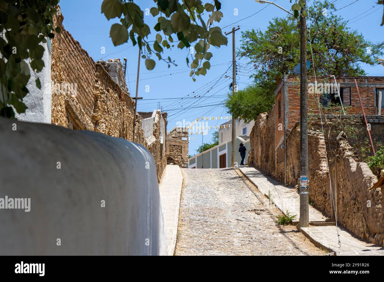 Una strada nella magica cittadina di Mineral de Pozos con una chiesa bianca sul retro. Foto Stock