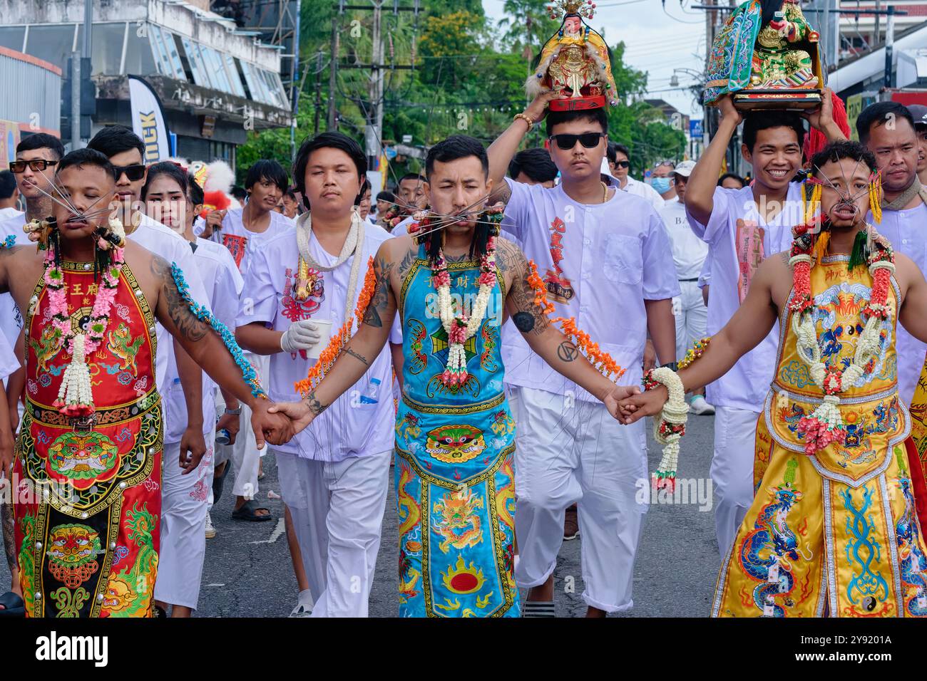 Durante il Vegetarian Festival nella città di Phuket, Thailandia, un gruppo di mezzi spirituali posa per le foto, con punte perforate attraverso le guance Foto Stock