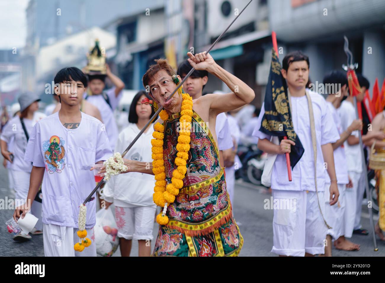 Durante il Festival vegetariano a Phuket, Thailandia, un mezzo Mah Song o Spirit mostra una lunga asta di metallo perforata attraverso la guancia Foto Stock