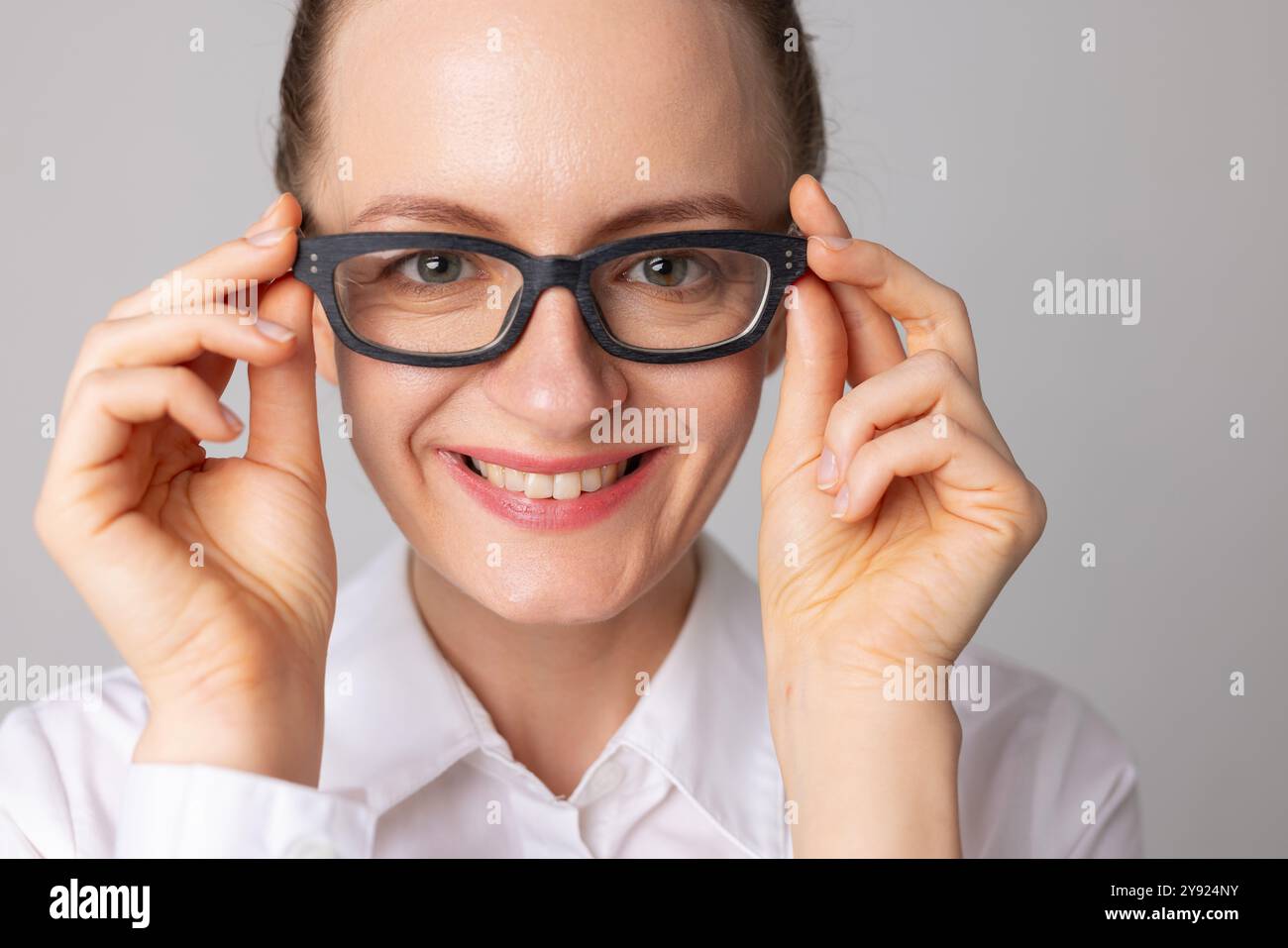 Una donna indossa gli occhiali per una buona visione e sorride perché può vedere meglio, il concetto di buona visione, la scelta degli occhiali Foto Stock