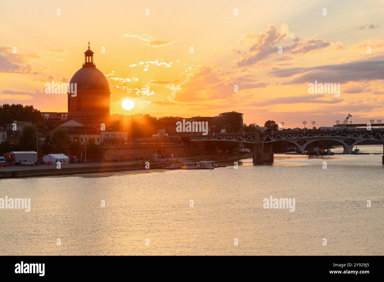 Tramonto dorato sul fiume Garonna con vista sul ponte pedonale di Saint-Pierre, Place Saint-Pierre e l'ospedale funerario visto dai riversi Foto Stock