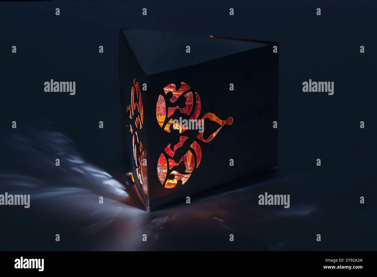 Pacchetto di zafferano geometrico illuminato con motivi intricati che si illuminano su uno sfondo scuro. Foto Stock