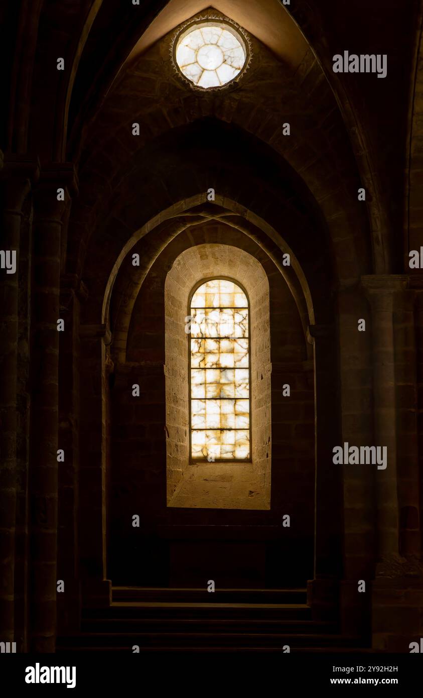 Una finestra in una stanza buia con un arco in pietra. Stile gotico. Il contrasto tra luce e ombre crea un'atmosfera di mistero Foto Stock