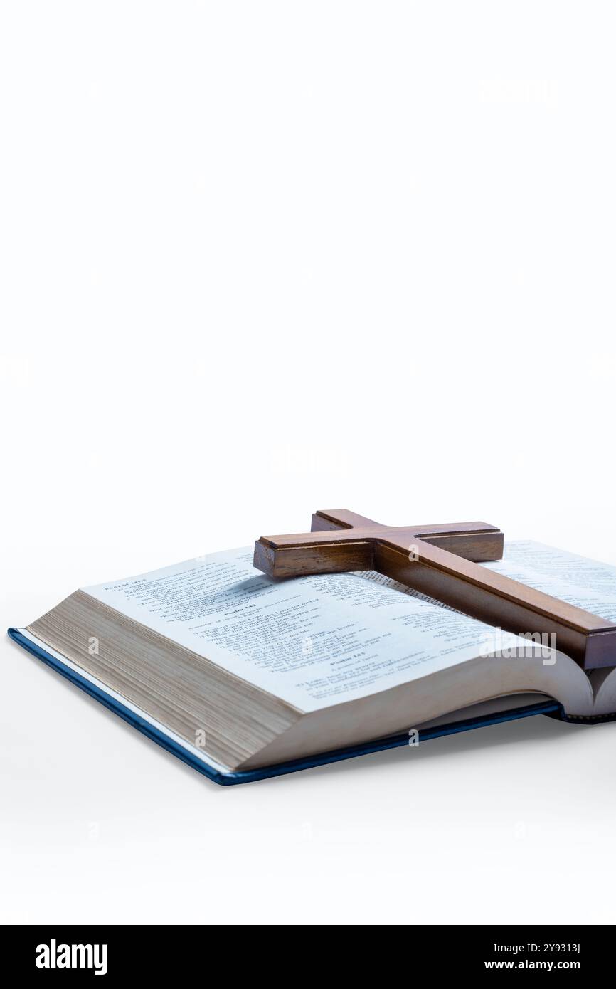 Croce religiosa in legno e libro blu aperto della Sacra Bibbia isolato su sfondo bianco. Sfondo cristiano, culto, chiesa, simboli, conce di preghiera Foto Stock