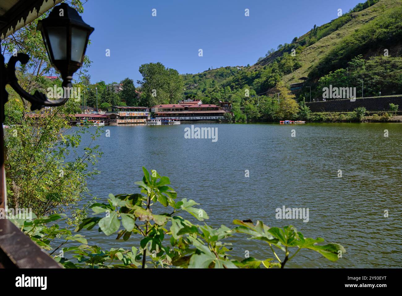 Lago di sera Gölü (lago Trabzon) a Trabzon, Turchia, vista della luce del giorno con persone in barca e ristoranti sullo sfondo. Foto Stock