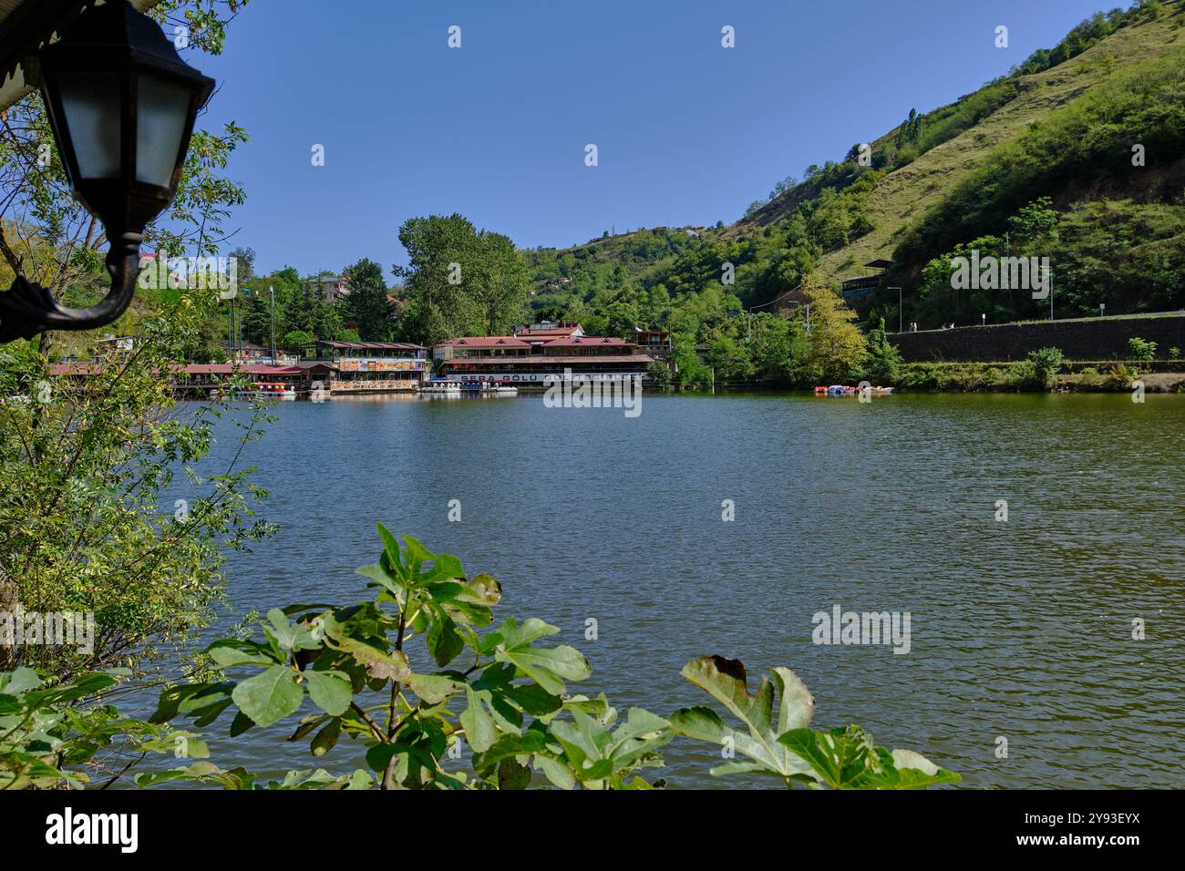 Lago di sera Gölü (lago Trabzon) a Trabzon, Turchia, vista della luce del giorno con persone in barca e ristoranti sullo sfondo. Foto Stock