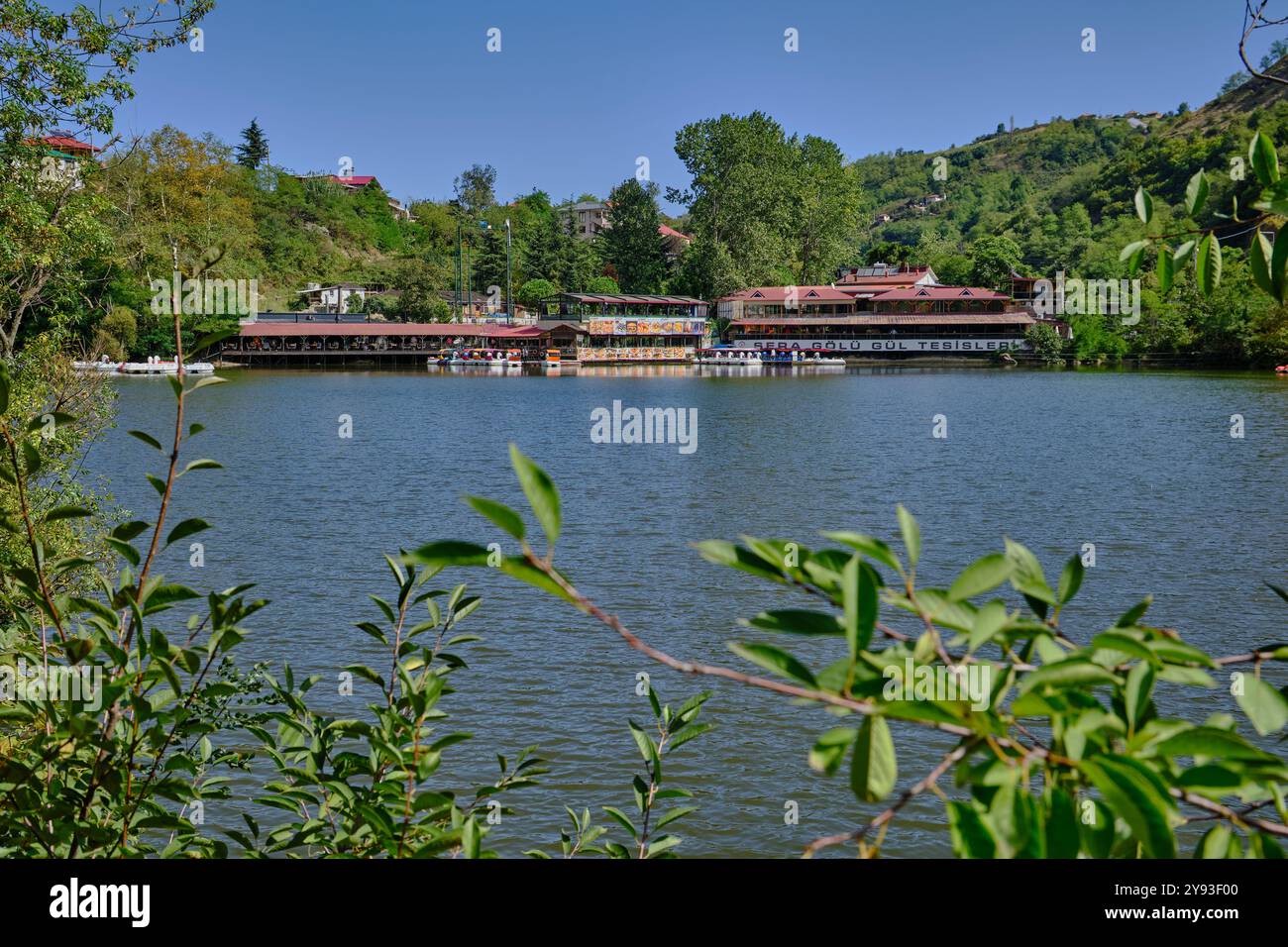 Lago di sera Gölü (lago Trabzon) a Trabzon, Turchia, vista della luce del giorno con persone in barca e ristoranti sullo sfondo. Foto Stock