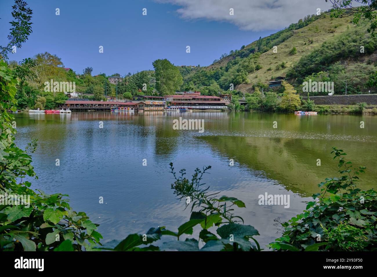 Lago di sera Gölü (lago Trabzon) a Trabzon, Turchia, vista della luce del giorno con persone in barca e ristoranti sullo sfondo. Foto Stock
