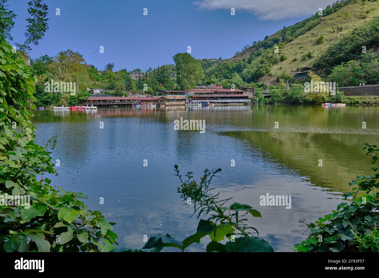 Lago di sera Gölü (lago Trabzon) a Trabzon, Turchia, vista della luce del giorno con persone in barca e ristoranti sullo sfondo. Foto Stock