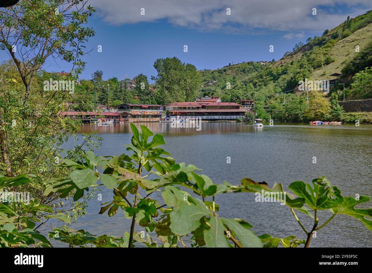 Lago di sera Gölü (lago Trabzon) a Trabzon, Turchia, vista della luce del giorno con persone in barca e ristoranti sullo sfondo. Foto Stock