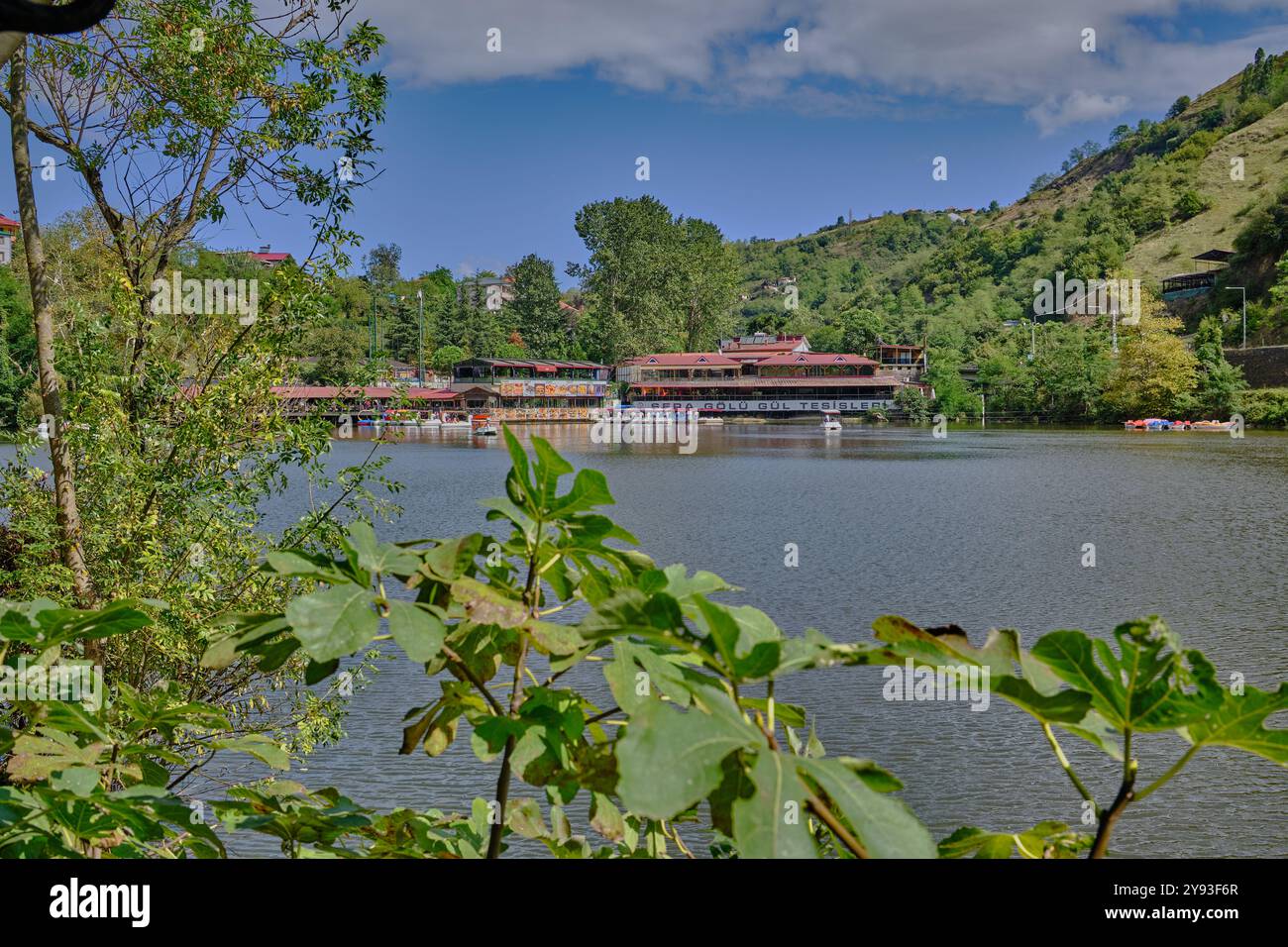 Lago di sera Gölü (lago Trabzon) a Trabzon, Turchia, vista della luce del giorno con persone in barca e ristoranti sullo sfondo. Foto Stock