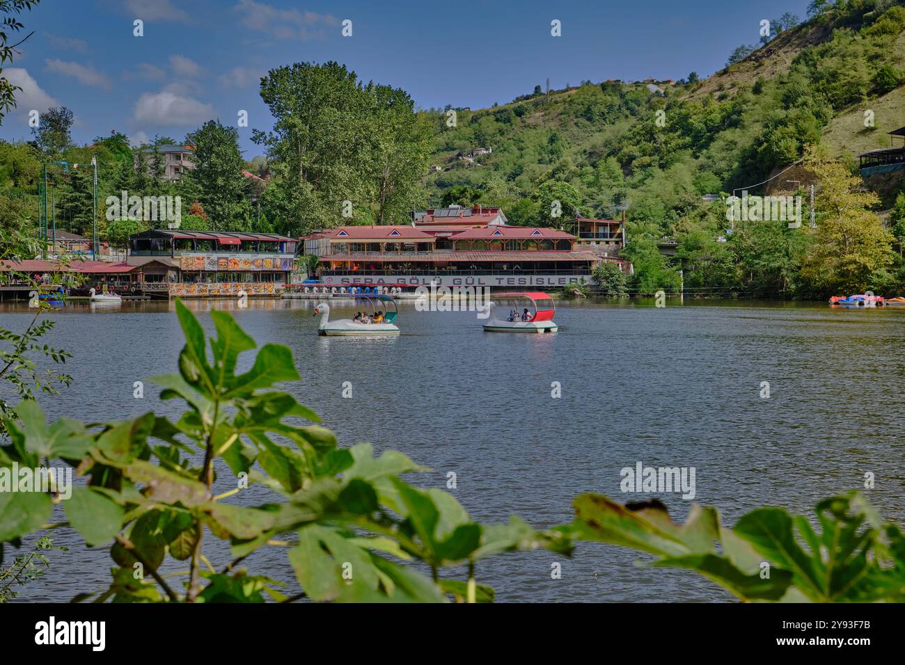 Lago di sera Gölü (lago Trabzon) a Trabzon, Turchia, vista della luce del giorno con persone in barca e ristoranti sullo sfondo. Foto Stock