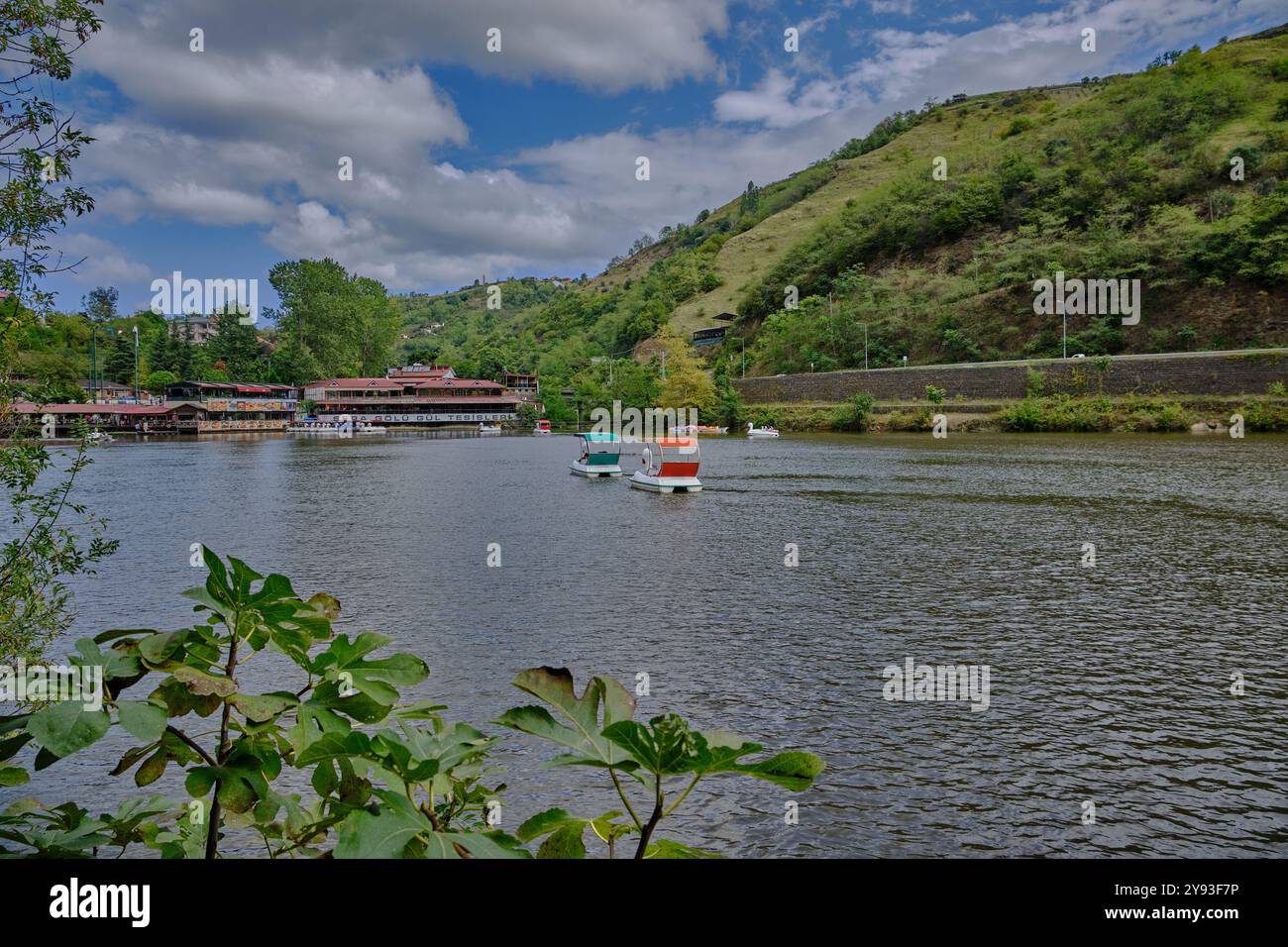 Lago di sera Gölü (lago Trabzon) a Trabzon, Turchia, vista della luce del giorno con persone in barca e ristoranti sullo sfondo. Foto Stock