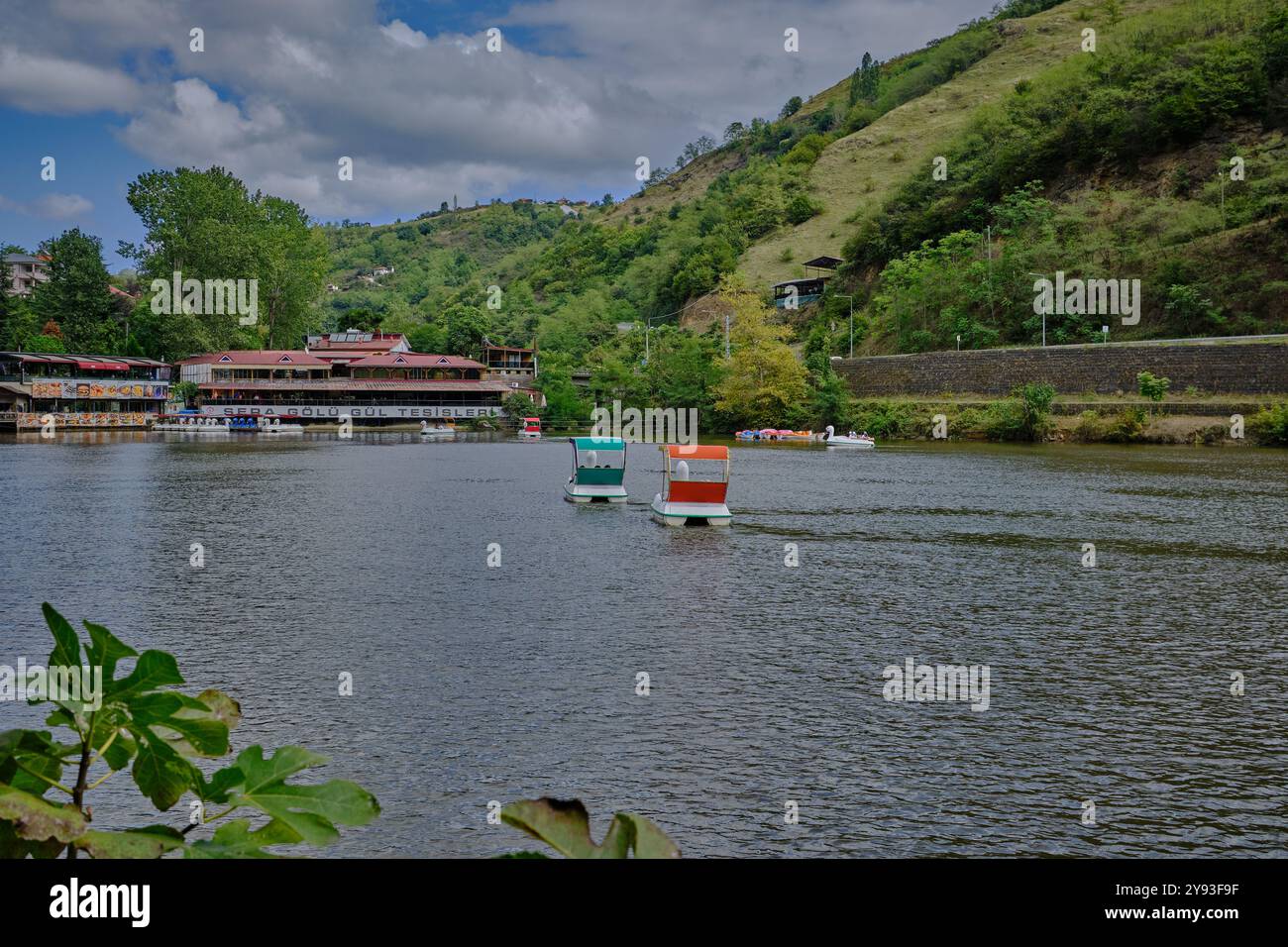 Lago di sera Gölü (lago Trabzon) a Trabzon, Turchia, vista della luce del giorno con persone in barca e ristoranti sullo sfondo. Foto Stock