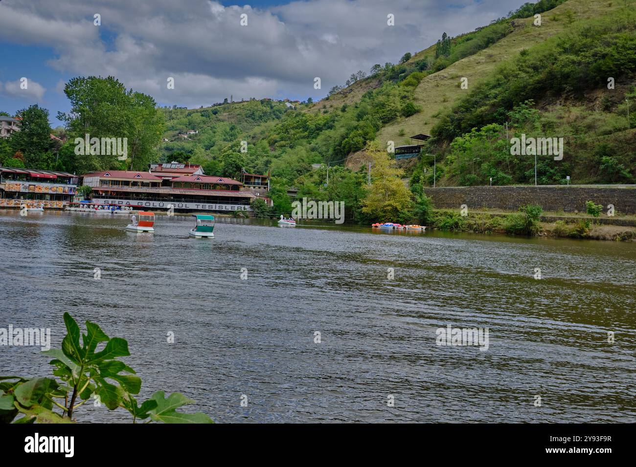 Lago di sera Gölü (lago Trabzon) a Trabzon, Turchia, vista della luce del giorno con persone in barca e ristoranti sullo sfondo. Foto Stock