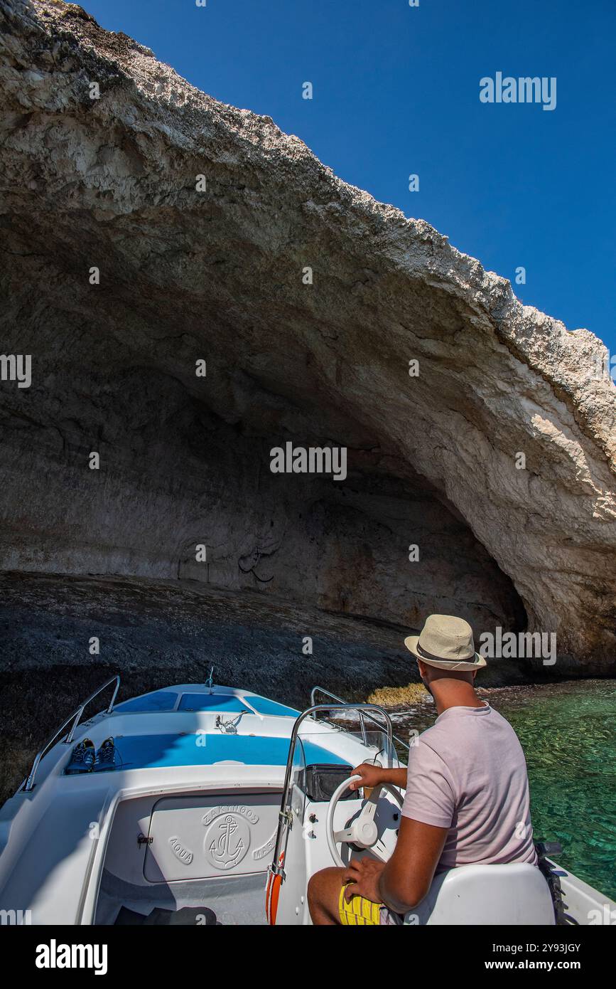 Skipper o autista di barca sull'isola greca di Zante o Zante che porta i turisti a vedere le grotte blu di agios Nikolaos nel nord dell'isola Foto Stock