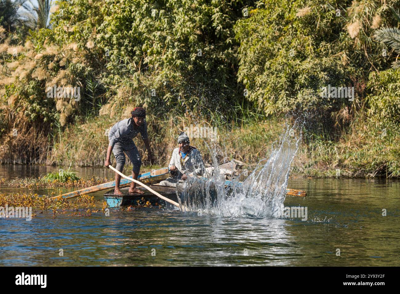 Pescatori di reti in barca a remi che praticano una tecnica di colpire la superficie dell'acqua per spingere i pesci nelle reti, villaggio di Ramadi, Egitto Foto Stock
