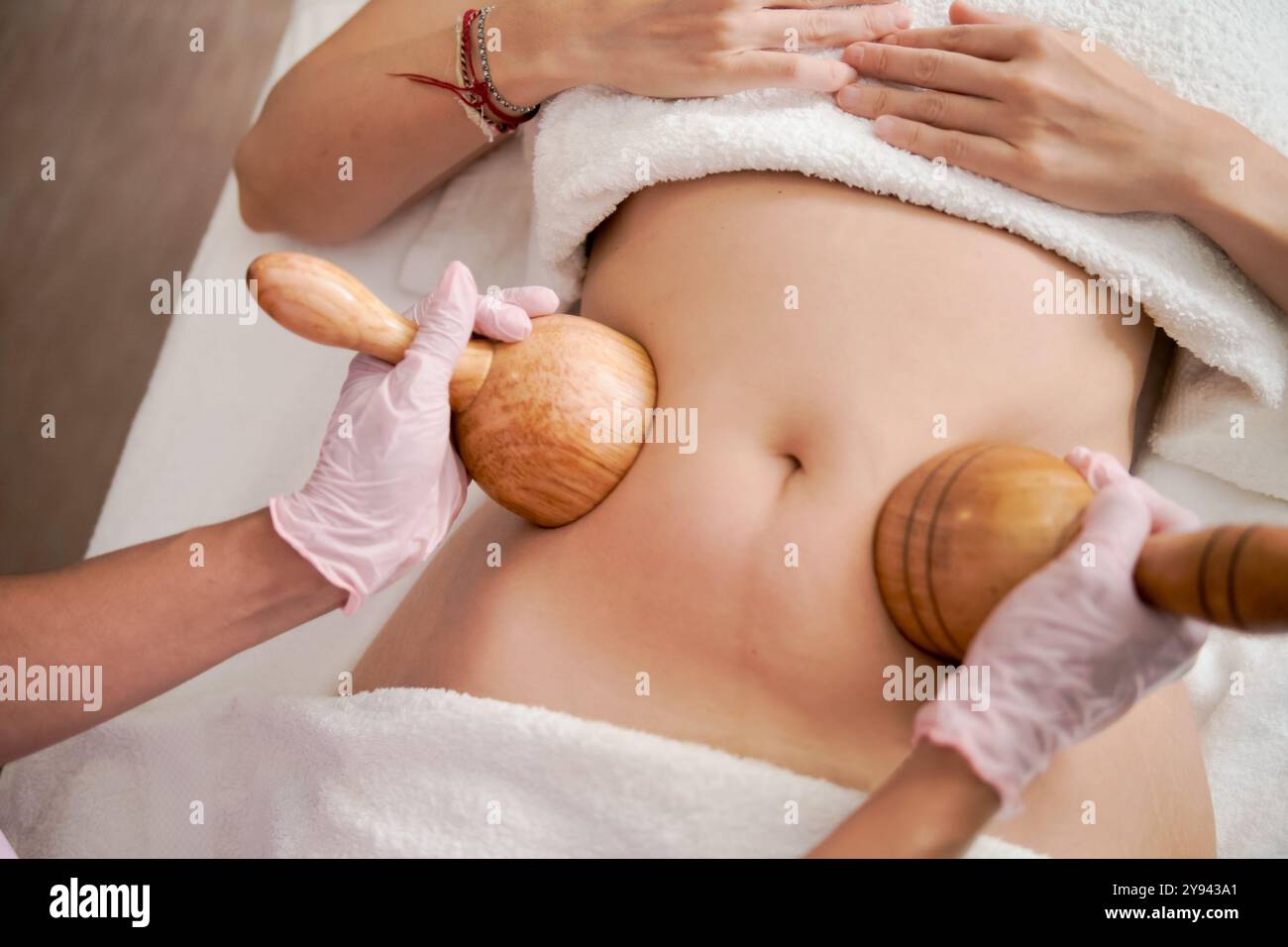 Donna corta e irriconoscibile che riceve un massaggio rilassante con strumenti di legno da parte di una terapista a casa. L'attenzione è dedicata al relax e al benessere. Foto Stock