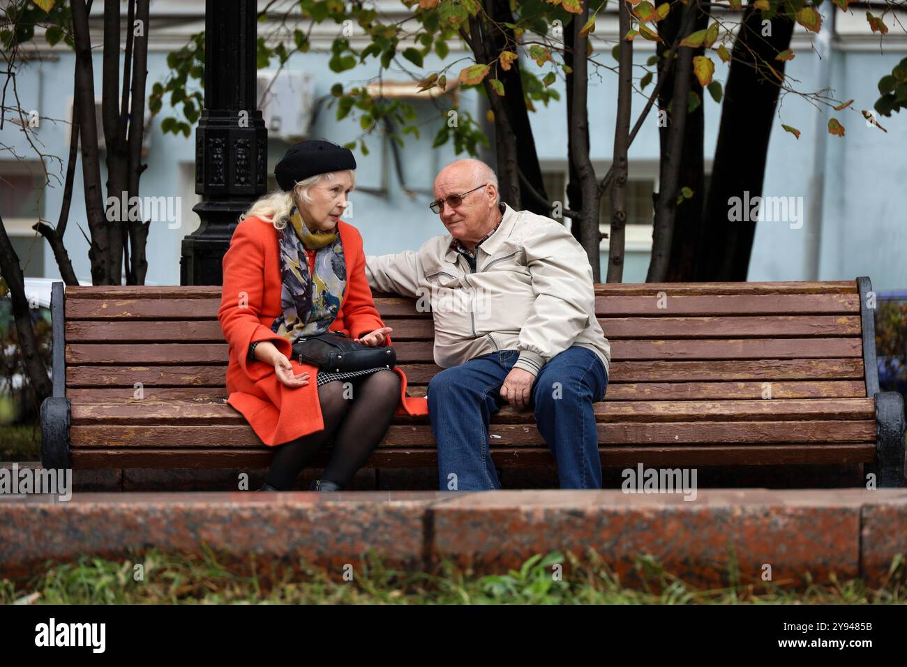 Una vecchia coppia che parla su una panchina nel parco autunnale, la vita in pensione Foto Stock