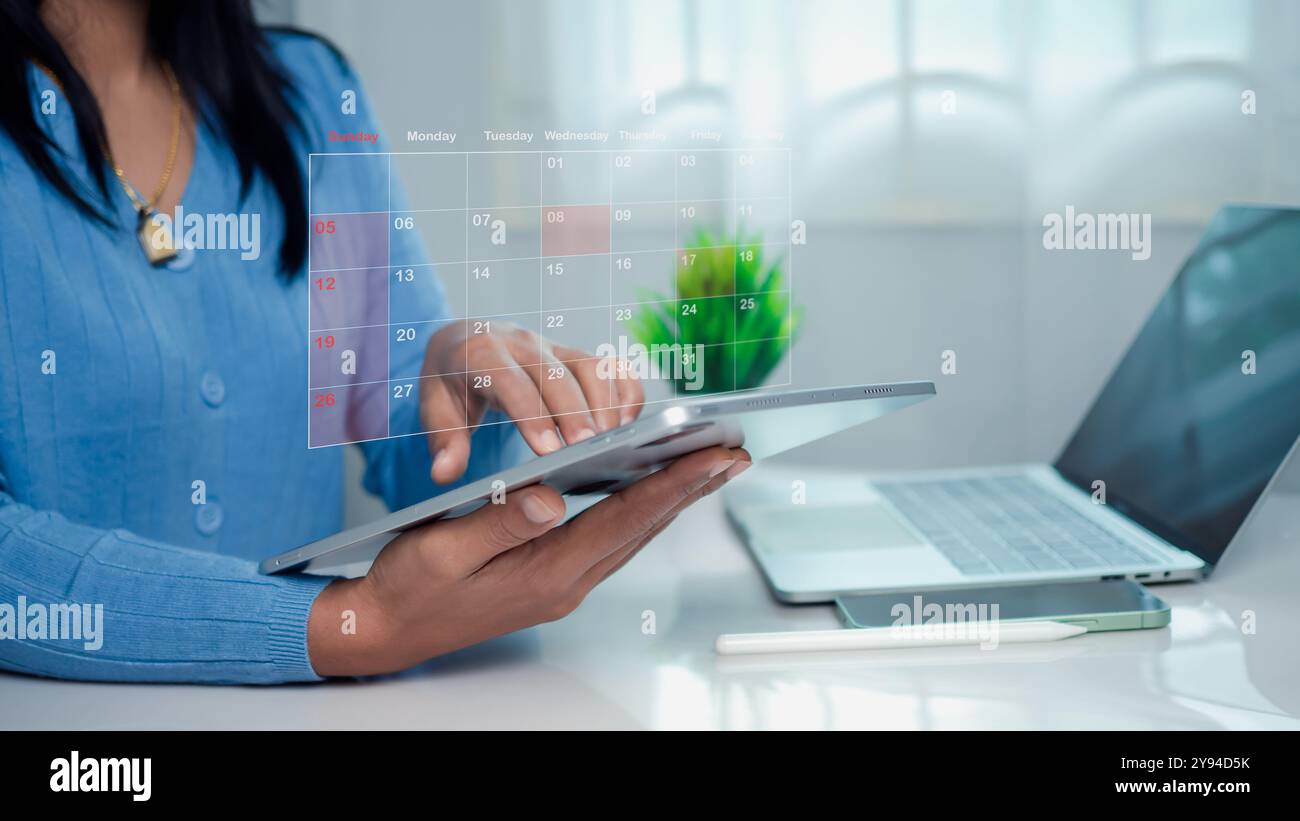 Donna d'affari che segna le date sul calendario virtuale con un tablet, gestisce il suo programma aziendale, imposta promemoria per appuntamenti importanti, co creativo Foto Stock