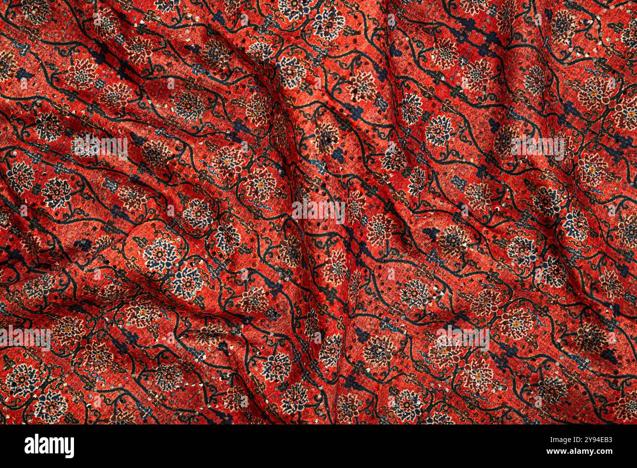 Un primo piano di tessuto rosso tradizionale con fantasie floreali complesse, ricco di design e texture culturali Foto Stock