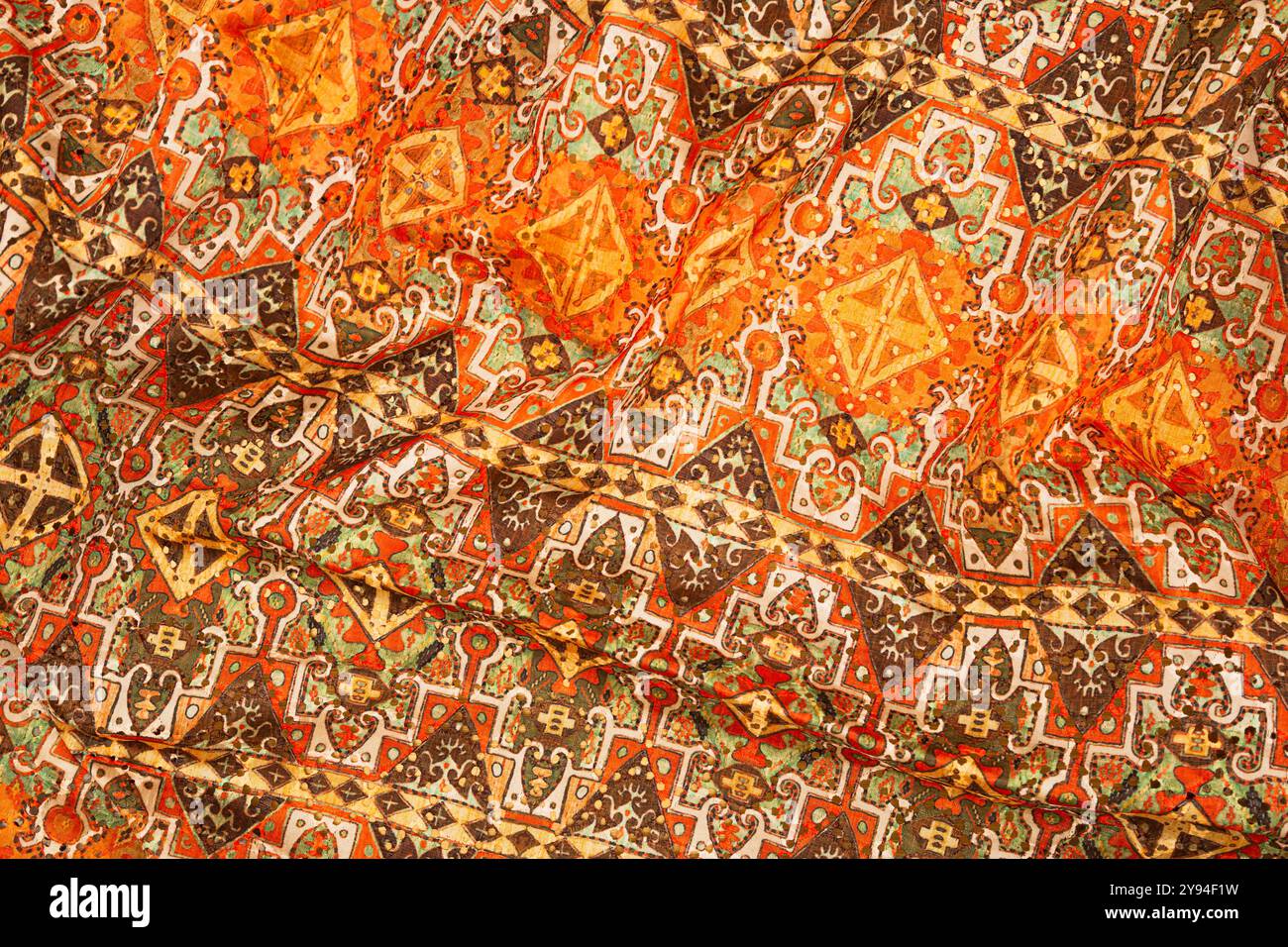 Tessuto tradizionale persiano con intricati motivi geometrici arancioni, marroni e verdi. Foto Stock