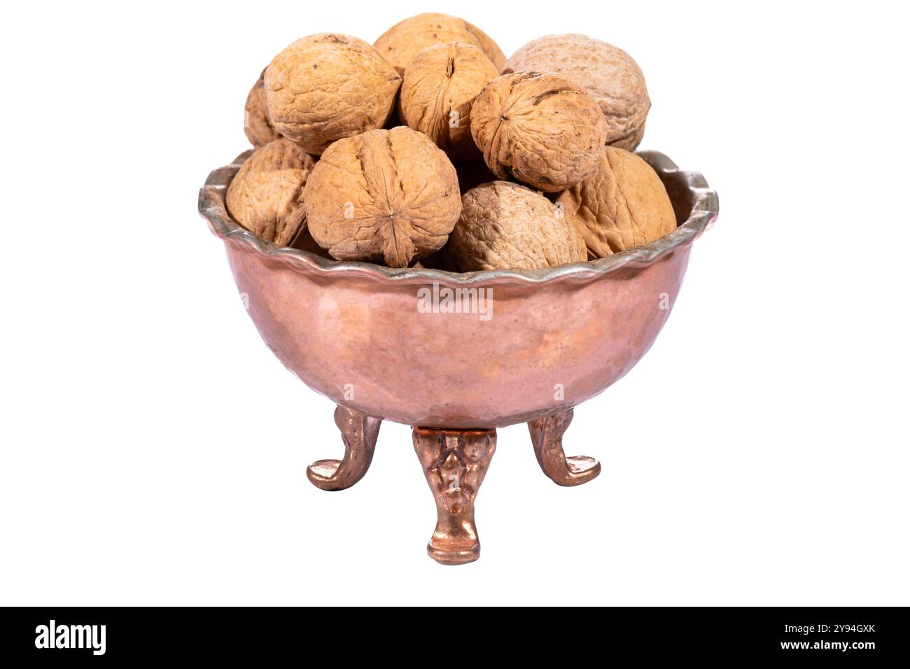 Le noci intere sono esposte in una ciotola di rame artigianale, che mette in risalto le texture naturali e le tonalità ricche e terrose Foto Stock