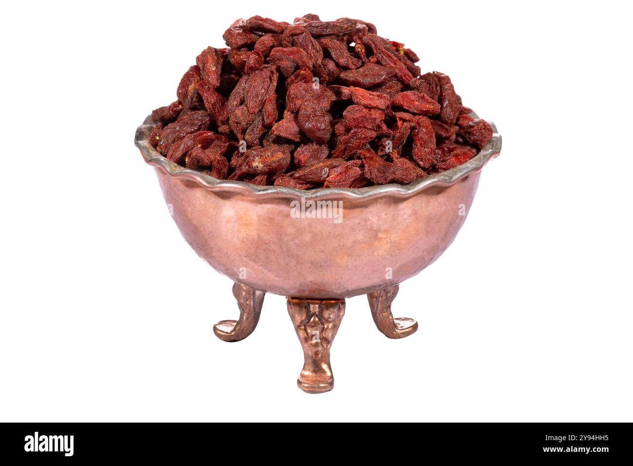 Bacche di goji essiccate in una ciotola decorativa in rame dallo stile rustico, isolata su sfondo bianco Foto Stock