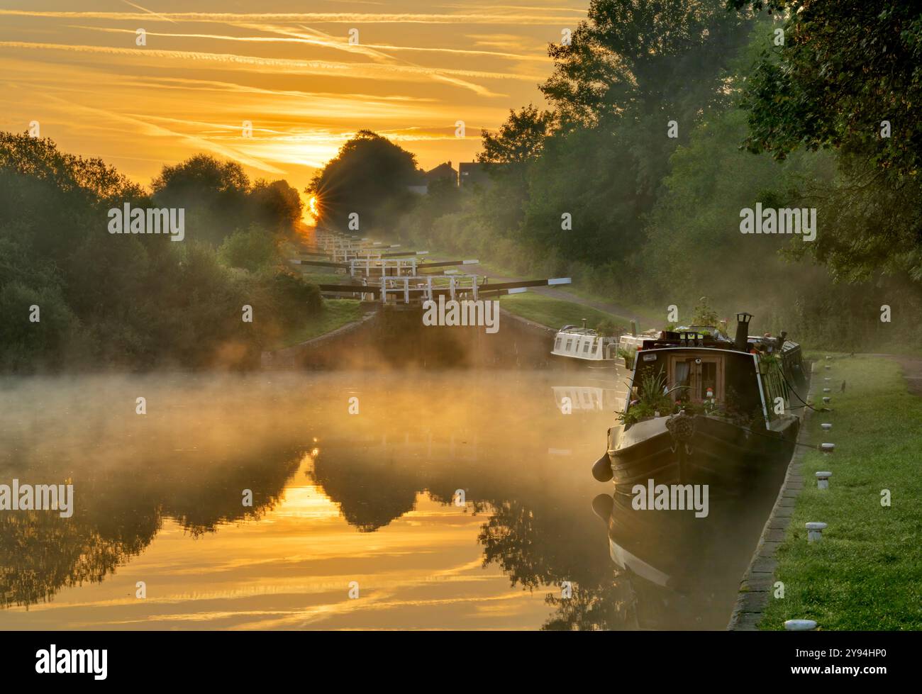 La collina di Caen si chiude all'alba, a Devizes, con bassa nebbia e una bella luce calda e barche sul canale ormeggiate Foto Stock