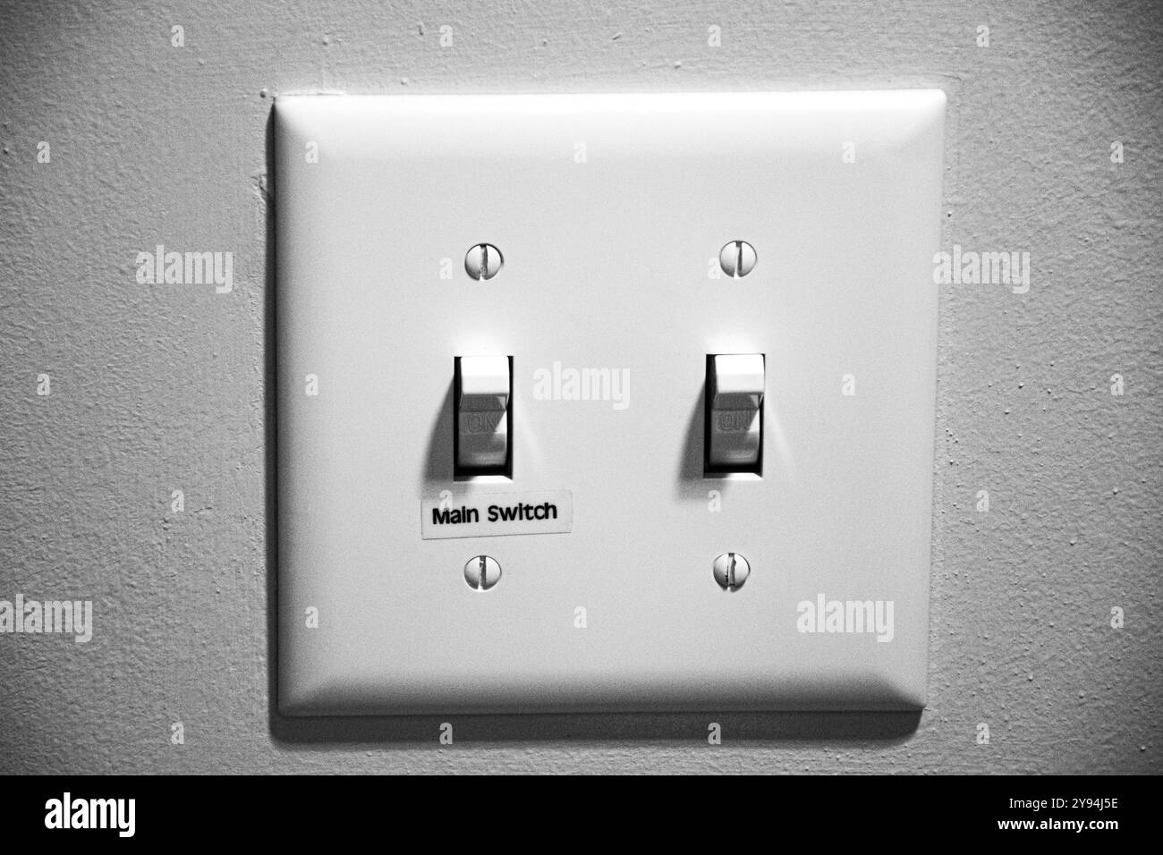 Foto in primo piano delle due bianco interruttori generali sul muro grigio e sia acceso Foto Stock