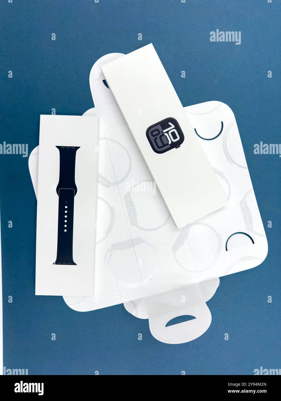Confezione con la nuova configurazione dello smartwatch Apple Watch serie 10 del 2024, unboxing e braccialetto intercambiabile su sfondo blu Design elegante - Immagine stock catturata con smartphone