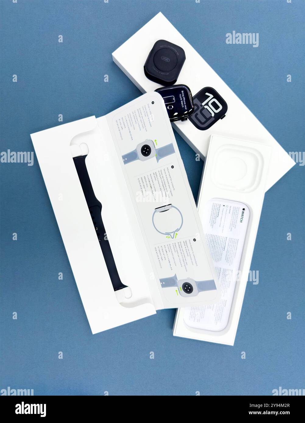 Confezione con la nuova configurazione dello smartwatch Apple Watch serie 10 del 2024, unboxing e braccialetto intercambiabile su sfondo blu Design elegante - Immagine stock catturata con smartphone