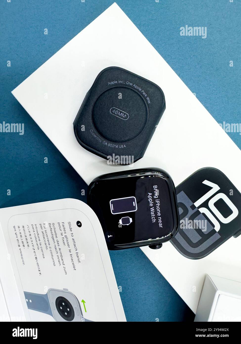 Confezione con la nuova configurazione dello smartwatch Apple Watch serie 10 del 2024, unboxing e braccialetto intercambiabile su sfondo blu Design elegante - Immagine stock catturata con smartphone