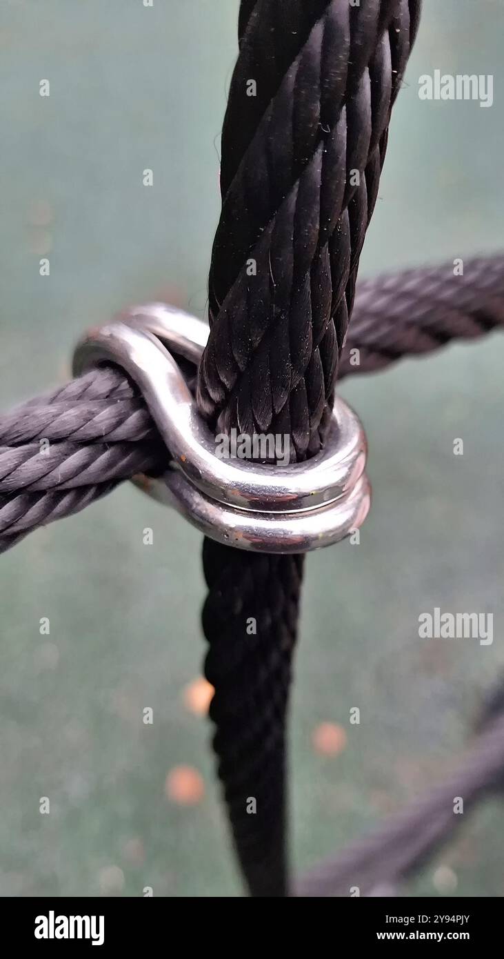 Primo piano della fune nera con morsetto metallico su sfondo verde Foto Stock