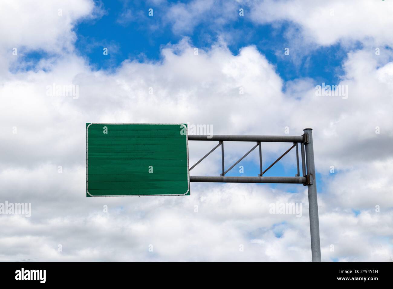 Segno verde vuoto della superstrada o della superstrada, vista ad angolo basso contro il cielo blu con nuvole Foto Stock