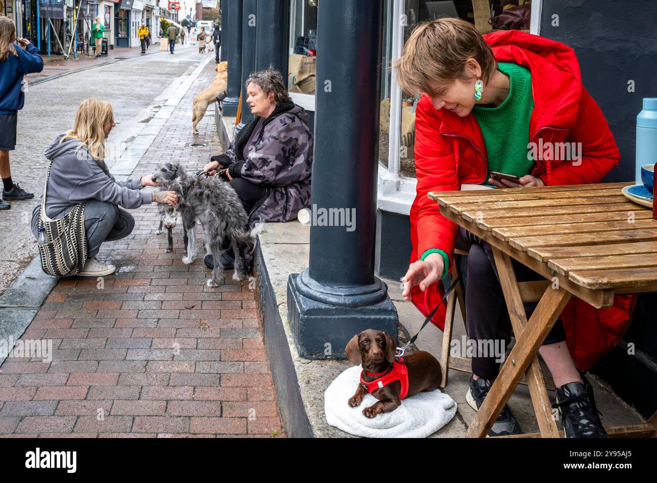 Gente del posto con i loro animali domestici seduti fuori Da Un Cafe in High Street, Lewes, East Sussex, Regno Unito. Foto Stock