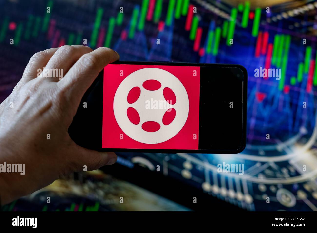 In questa illustrazione fotografica, il logo Polkadot (DOT) visualizzato su uno smartphone con grafici del mercato azionario sullo sfondo. Foto Stock