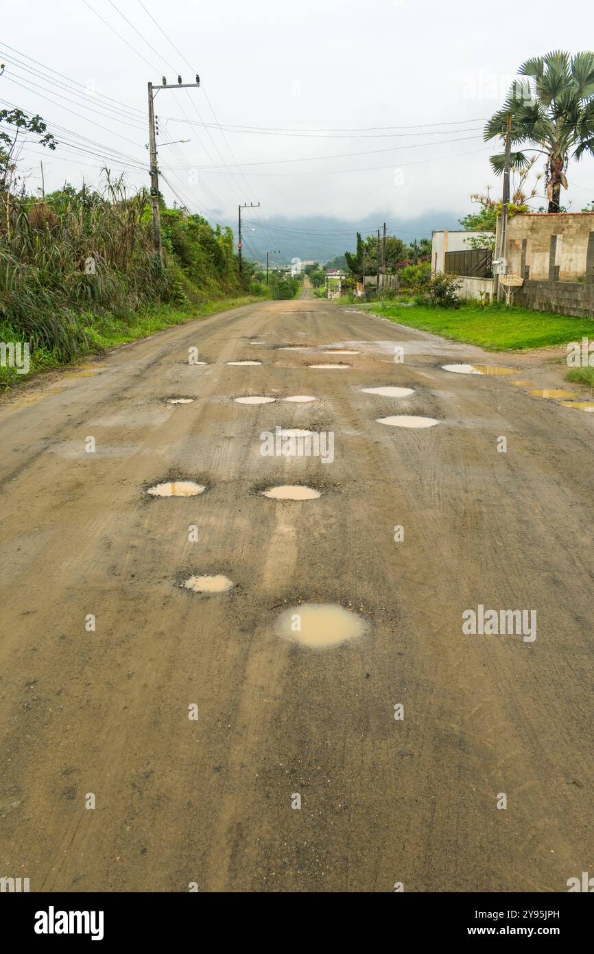 Molte buche su una strada sterrata in un quartiere residenziale di Schroeder, Santa Catarina, Brasile Foto Stock