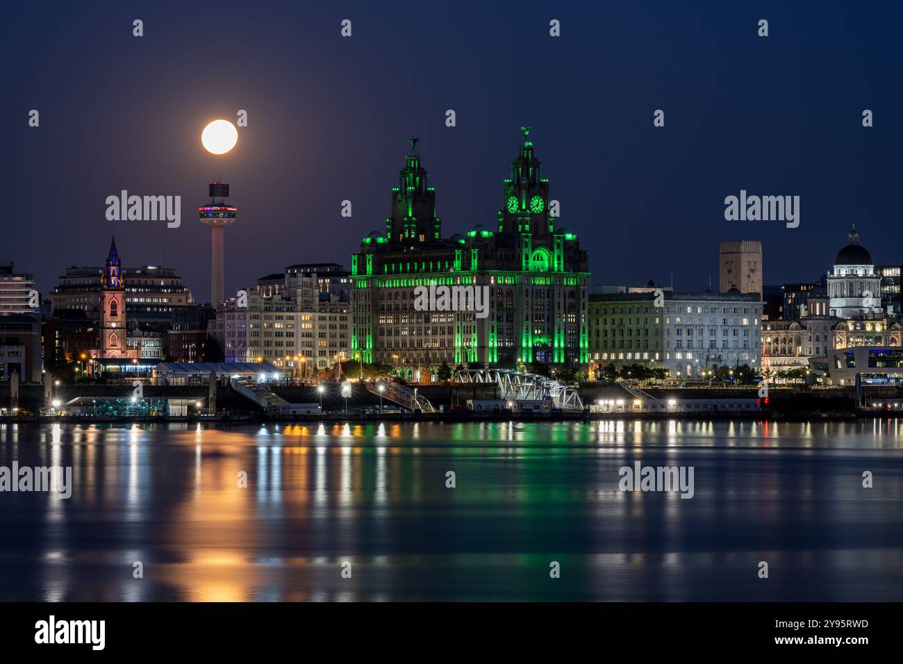 Una luna piena sorge sul fiume Mersey e sullo skyline di Liverpool, incluso il monumento Royal Liver Building. Foto Stock